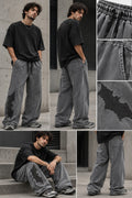 Model wearing grey washed oversized trousers with black appliqué and oversized black tee